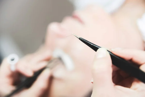 Young woman putting false lashes at beauty salon