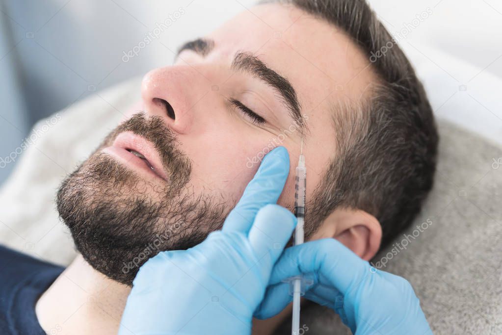 Close up of young man having hyaluronic fillers in his face