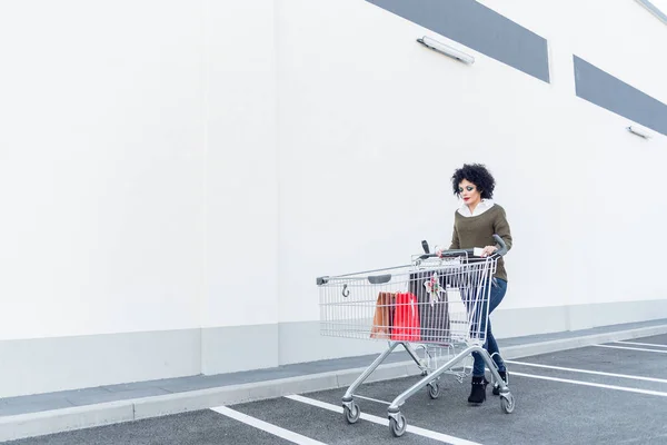 Elinde Çanta Alışveriş Sepeti Iterek Genç Güzel Kadın — Stok fotoğraf