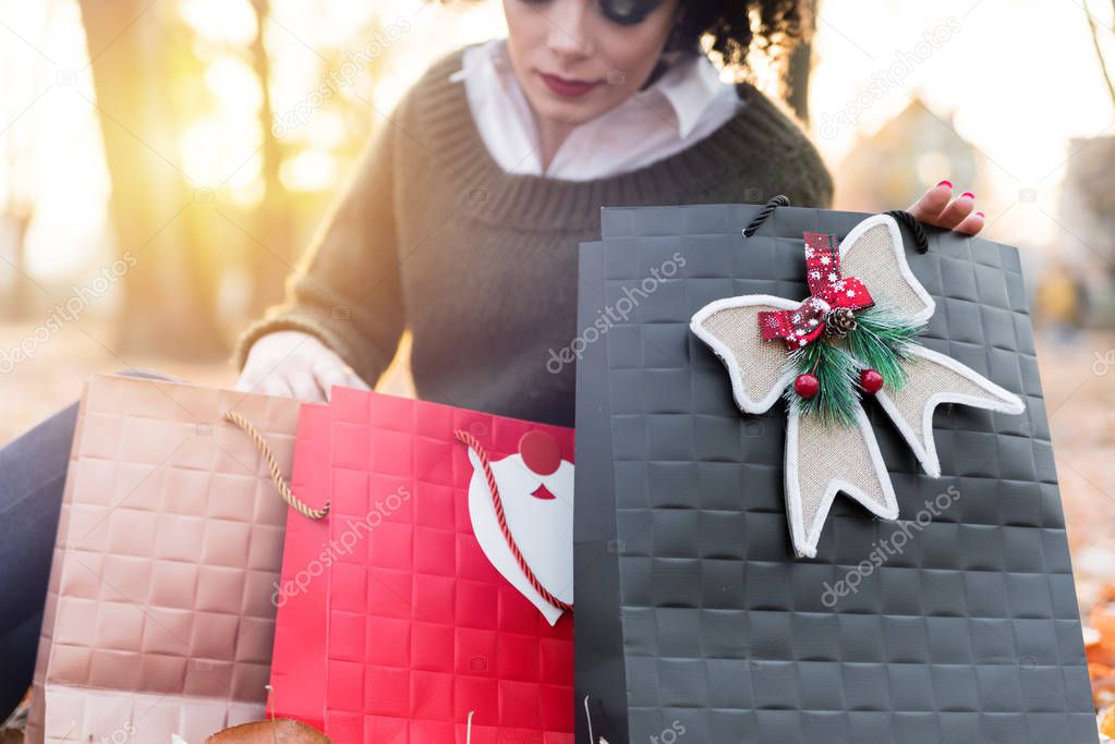 Front view of young woman with christmas bags sitting outside