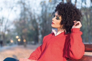 Kırmızı kazaklı oturma parkta bankta genç güzel kadın 
