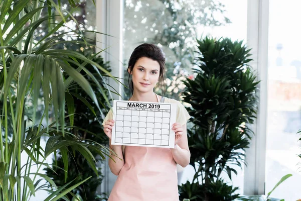 Beautiful Young Florist Holding Calendar Spring 2019 Greenhouse — Stock Photo, Image
