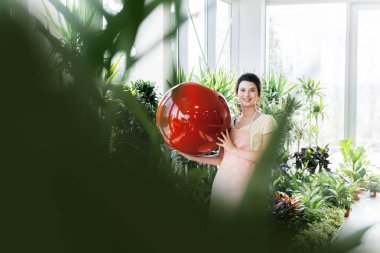 Genç profesyonel çiçekçi gösteren saksı sera içinde 