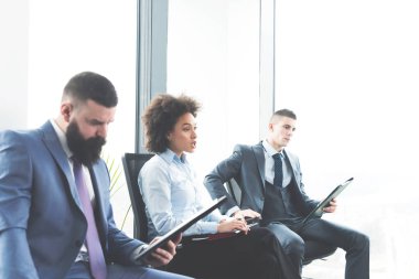 kadın onun yanında bekleme odasında oturup iki erkek adaylar ise büyük modern firmasında iş görüşmesi için hazırlanıyor