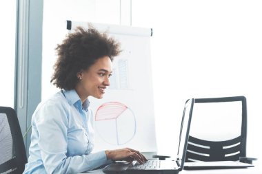 parlak modern ofis içinde laptop üzerinde çalışırken masada oturan genç kız