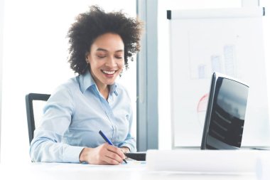 parlak modern ofis içinde laptop üzerinde çalışırken masada oturan genç kız
