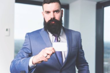 Kameraya bakarak ve tutarak onun kimlik kartı, metin alanı ile boş beyaz kartı modern hipster işadamı portresi