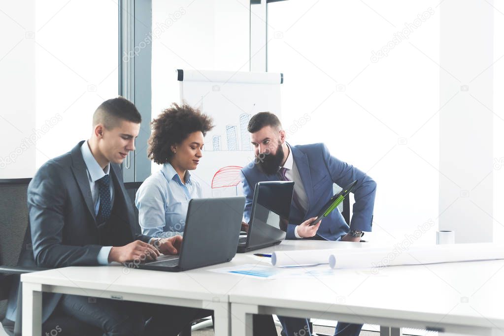 Three business partners discussing strategy at meeting in conference room