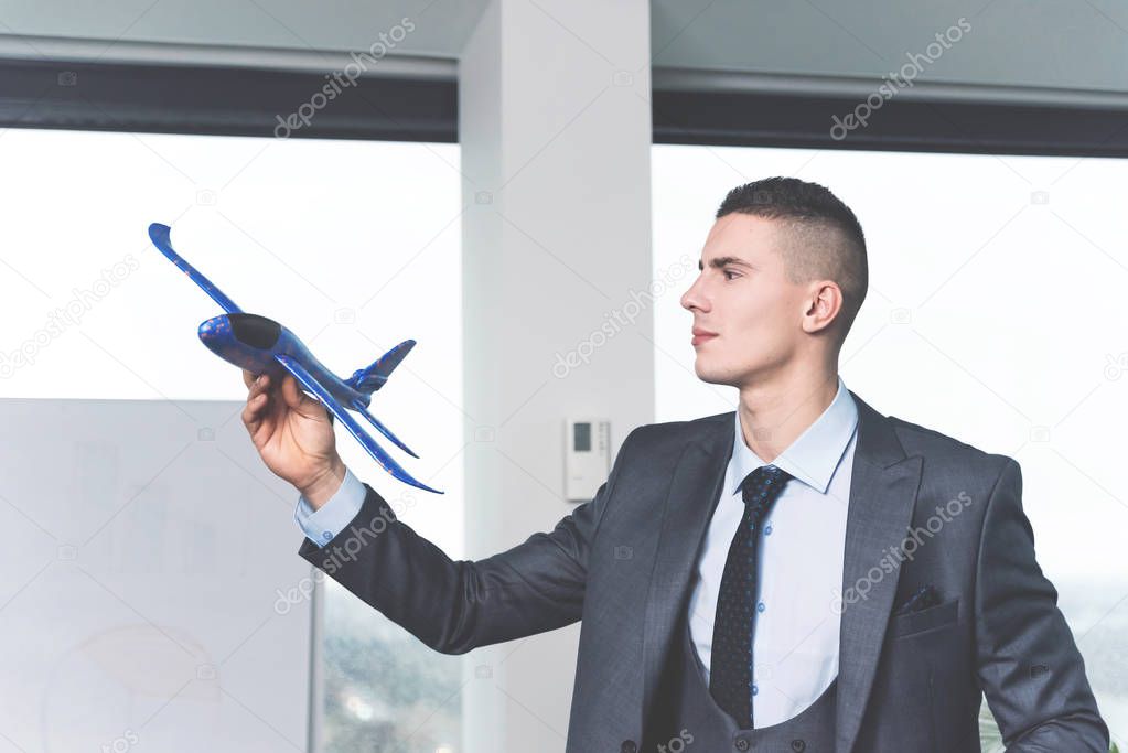 young businessman playing with airplane model at modern office 
