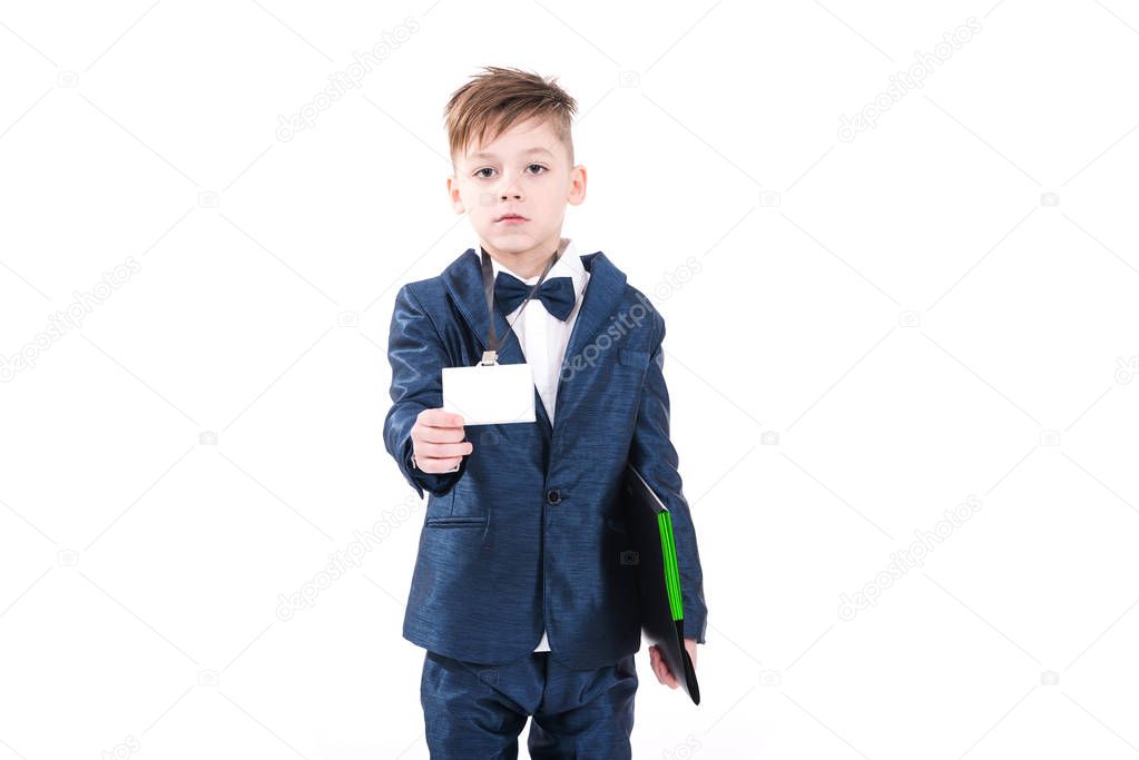 Serious concentrated ambitious little boy in business suit looking at camera and holding ID card and files