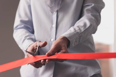 Closeup açılış töreninde makas ile kırmızı kurdele kesme üst düzey kadın elleri fotoğraf kırpılmış