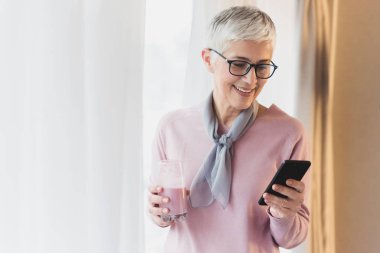Cep telefonu metin mesajları okuma modern kısa gri saçlı güzel olgun kadın