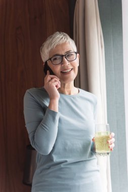 Onun cep telefonu konuşurken modern gözlüklü Olgun kadın portresi