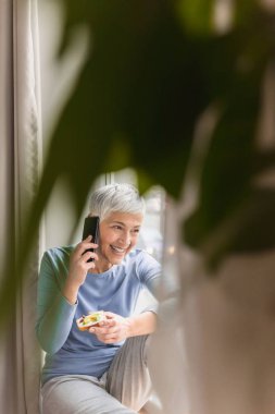 parlak ana penceresinde onu telefonla konuşurken büyük muhteşem gülümseme ile üst düzey kadın