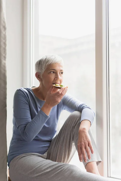 Mujer Madura Sentada Junto Ventana Casa Comiendo Desayuno Saludable Mientras — Foto de Stock