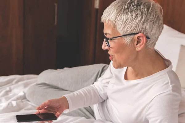 mature woman using app for smart house system on her mobile phone