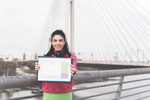 Atractiva Morena Deportiva Sosteniendo Papel Con Plan Para Entrenar Mirando — Foto de Stock