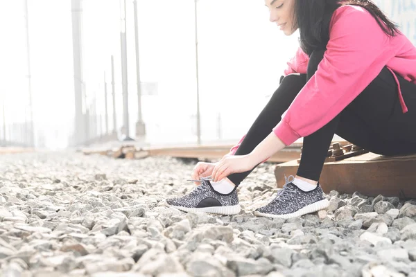 穿着运动服的迷人年轻女子将鞋带绑在运动鞋上 准备街头锻炼 — 图库照片