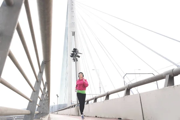 Sportliche Junge Frau Joggt Auf Brücke Und Hört Ihre Workout — Stockfoto
