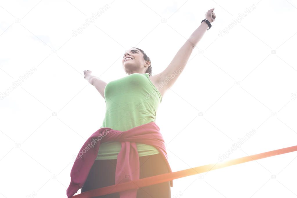 Sporty young woman celebrating victory on finish line of race