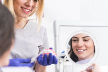 Onun hastaya uygun diş temizliği gösteren dostu gülümseme ile Güzel profesyonel kadın diş hekimi 