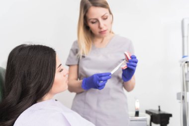 Onun hastaya uygun diş temizliği gösteren dostu gülümseme ile Güzel profesyonel kadın diş hekimi 