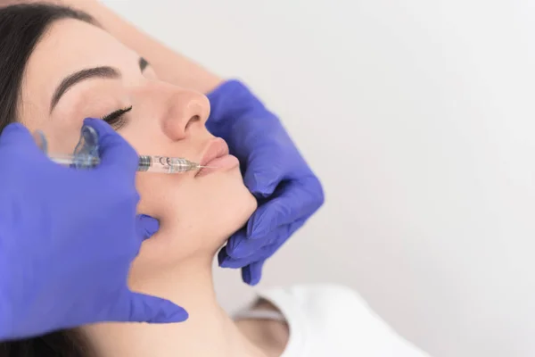 Profile of attractive female patient having her lower lip injected with filler