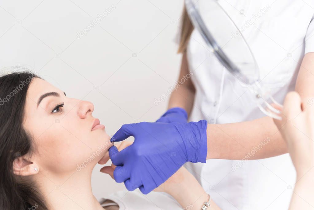 Close up of doctors hands checking patient chin after corrective procedure