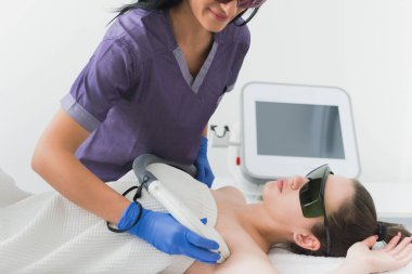 Emin neşeli kozmetolog hastalarda koltuk altı epilasyon için lazer tedavisi yapıyor 