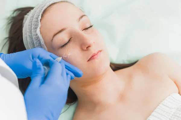 若い女性患者の頬にヒアルロン酸充填剤を注入する医師 — ストック写真