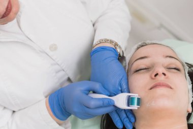 Hastalar yüz üzerinde rulo tedavi yapan dermatolog Kırpılmış görünümü