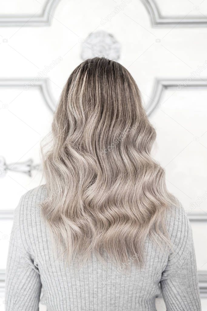 Back view of girl with beautiful blond sombre hairstyle standing in hair salon, Balayage technique concept