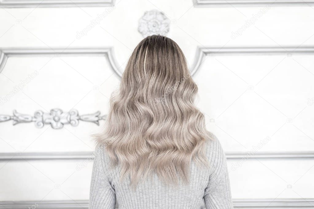 Back view of girl with pretty blond ombre hairstyle standing in hair salon, Balayage technique concept