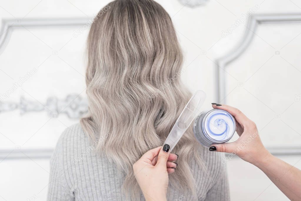 Female hands holding  cosmetic mask for colored hair, Balayage technique concept 