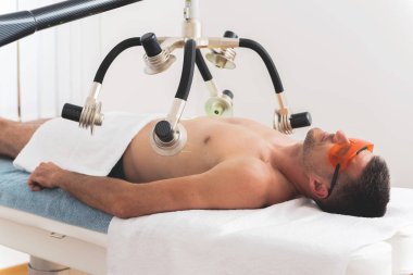 Modern klinikte non invaziv lazer vücut şekillendirme tedavisi olan adam 