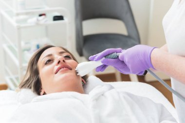 Woman in beauty center having multipolar radiofrequncy treatment for her facial skincare  clipart