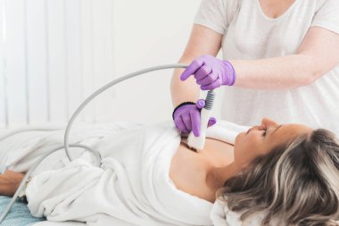 Cropped photo of female hands doing multipolar radiofrequncy treatment on a beautiful woman clipart