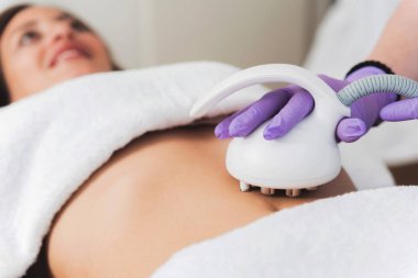 Close up of woman having multipolar radiofrequncy treatment for body shaping and tightening on her belly  clipart