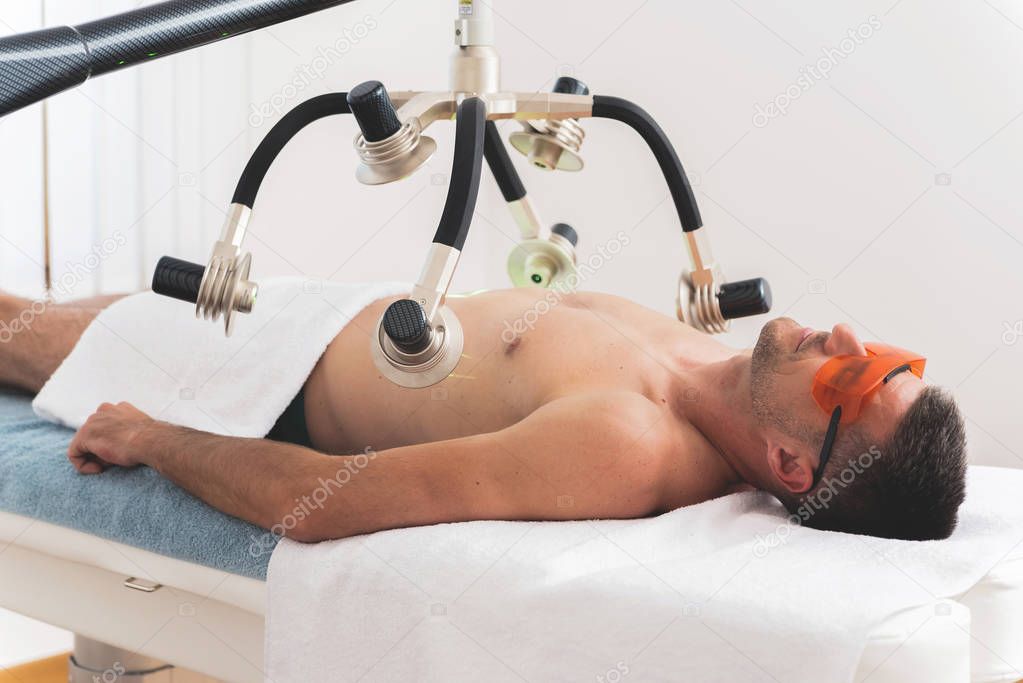 Man having non invasive laser body shaping treatment in modern clinic 