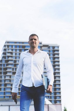 Modern kentsel binaların önünde duran rahat kendinden emin adam Ön görünümü 