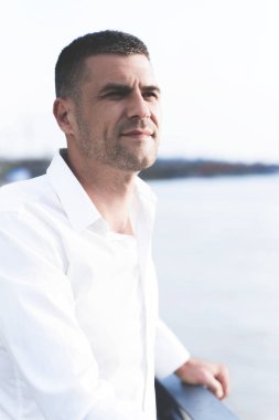 Nehir kıyısında köprüde duran dikkatli yakışıklı adamın portresi 