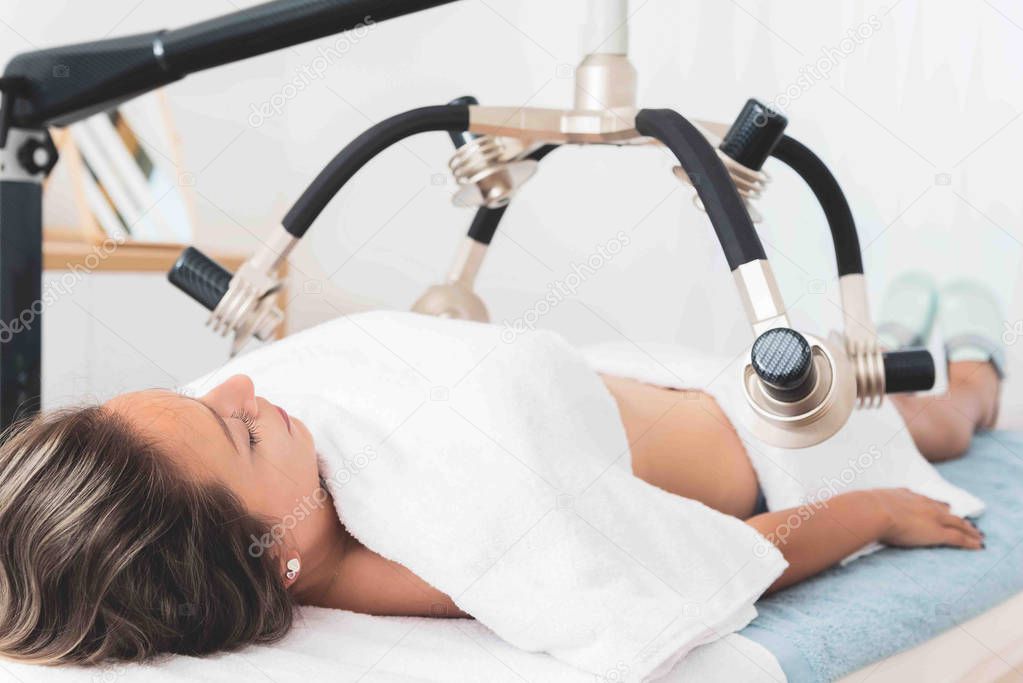 Woman having laser body shaping treatment in aesthetic clinic 