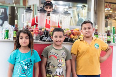 Bağdat, Irak - 29 Haziran 2019: Meyve suyu standı önünde üç pozitif çocuk poz verdi