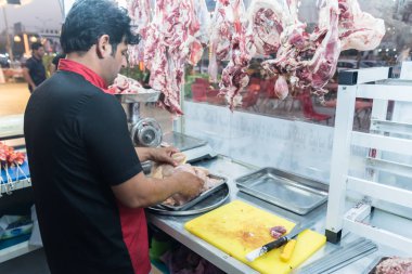 Irak, Bağdat - 08 Temmuz 2019: Kasap eti satışa hazırlıyor. Arka planda bir sürü taze et var. Kasap dükkanı.
