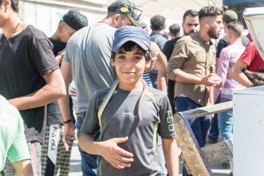 Irak, Bağdat - 05 Temmuz 2019: Sokak pazarında yılanı tutan genç çocuk. Tehlikeli yoldan para kazanmak..