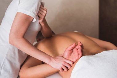Bir spa kliniğinde lomi masajı yaptıran genç bir sporcunun arka plan görüntüsü.