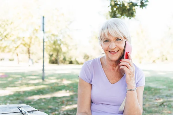 Neşeli Yaşlı Kadın Akıllı Telefondan Koşup Konuştuktan Sonra Parkta Dinleniyor — Stok fotoğraf