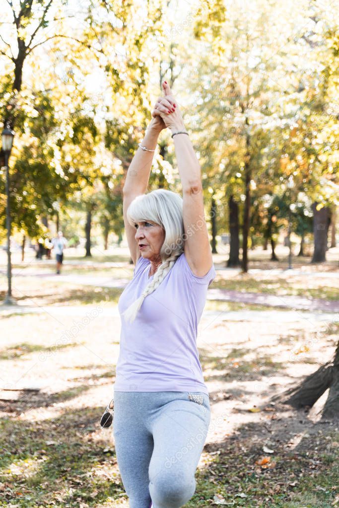 Senior woman making yoga at park, healthy lifestyle concept