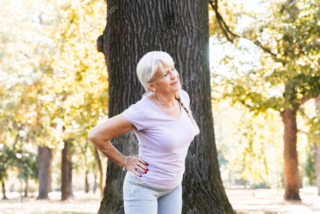 Closeup of senior woman doing fitness workout in park and stretching, healthy lifestyle concept