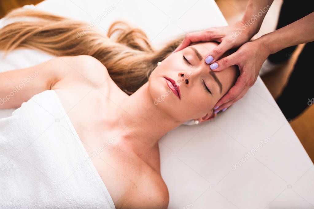 Beautiful young woman relaxing with hand massage at beauty spa. Face massage. Closed up of young beautiful woman getting spa massage treatment at beauty spa salon.